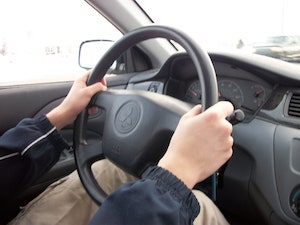 person with hands on a car steering wheel
